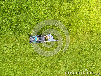 Beautiful girl cuts the lawn. Mowing lawns. Aerial view beautiful woman lawn mower on green grass. Mower grass equipment. Mowing g Editorial Stock Photo