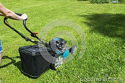 Beautiful girl cuts the lawn. Mowing lawns. Lawn mower on green grass. mower grass equipment. mowing gardener care work tool Stock Photo