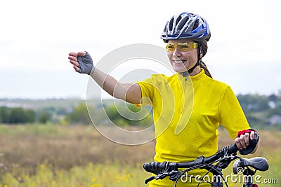 Beautiful girl cyclist in yellow points her hand forward Stock Photo