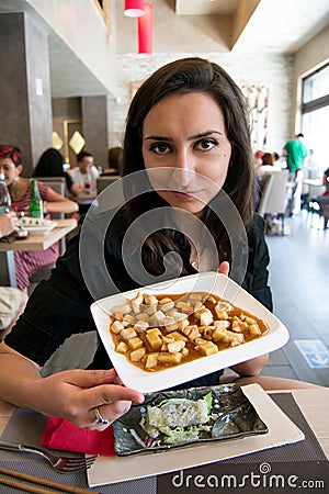 Beautiful girl with dark hair, dressed in black is holding a plate full of delicious food Stock Photo