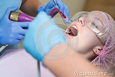 Beautiful girl in dental chair on the examination at dentist. Woman showing her perfect straight white teeth. Technology Stock Photo