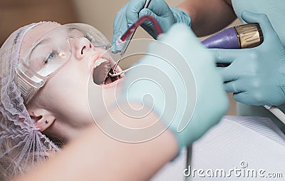 Beautiful girl in dental chair on the examination at dentist. Woman showing her perfect straight white teeth. Technology Stock Photo