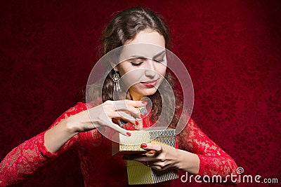 Beautiful girl dissatisfied with a small gift in a red dress. Stock Photo