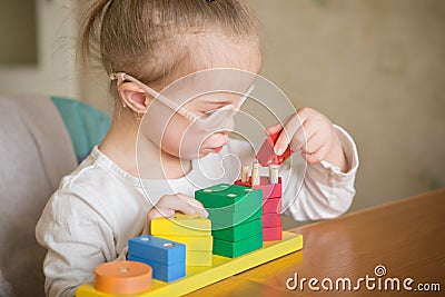 Beautiful girl with Down syndrome sorts geometric shapes Stock Photo