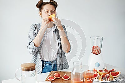 Beautiful girl eating grapefruit piece over white wall. Healthy fitness nutrition. Copy space. Stock Photo