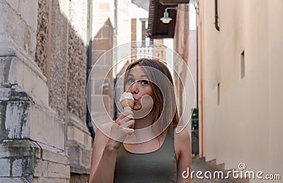 Young woman eating ice cream in an alley Stock Photo