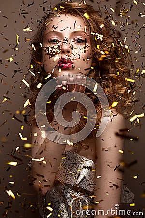 Beautiful girl in an evening dress and gold curls. Model in New Year`s image with glitter and tinsel. Stock Photo