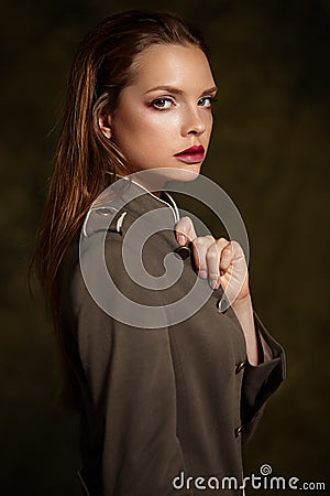 Beautiful girl in fashionable coat on dark background. Stock Photo