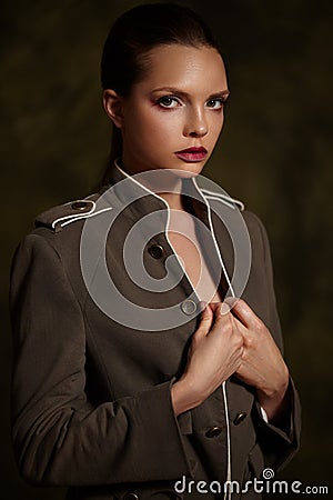 Beautiful girl in fashionable coat on dark background. Stock Photo