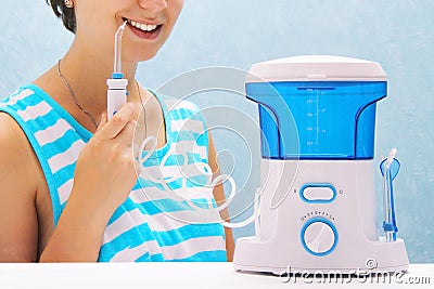 Beautiful girl flushes her teeth with an oral irrigator. the woman smiles and holds the irrigator handle. cleaning of teeth at hom Stock Photo
