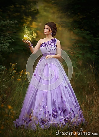 Beautiful girl in a gorgeous purple long dress, holding a candle Stock Photo