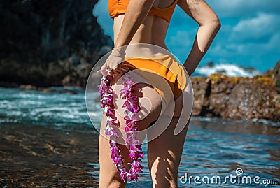 Beautiful girl with hawaiian lei flower resting near ocean on beach. Tanned young woman on vacation at resort. Concept Stock Photo