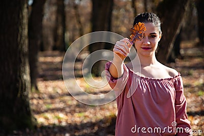 Beautiful girl holding a brown leaf covering her eye Stock Photo