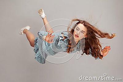 Beautiful girl levitating in mid-air, falling down and her hair messed up soaring from wind, model flying hovering with dreamy Stock Photo