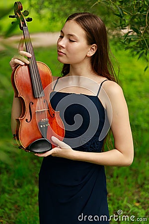 a beautiful girl with long violinists stands in the park in the summer Stock Photo