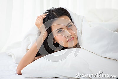 beautiful girl lying down in blanket on bed Thinking something and looking up . Young asian woman waking up early in the morning Stock Photo