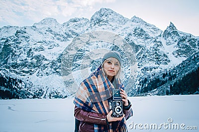 Beautiful girl makes a photo on an old vintage camera. In the mountains in winter, adventure and travel Stock Photo