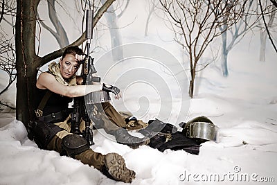 The beautiful girl in a military uniform with the weapon sits Stock Photo