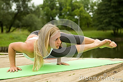 A beautiful girl performs a stand on the arms of Ashtavakrasana. Stock Photo