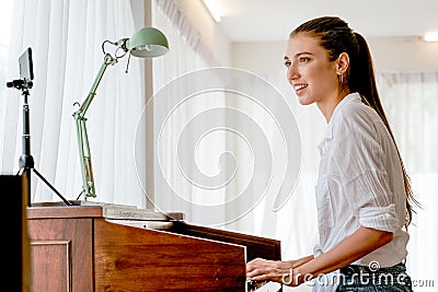 Beautiful girl play electone in room and live on social media and also sing song with happy emotion Stock Photo