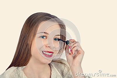 A beautiful girl is putting mascara on her eyelashes Stock Photo