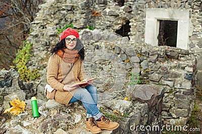 Beautiful girl read book near old castle. Autumn time. Stock Photo