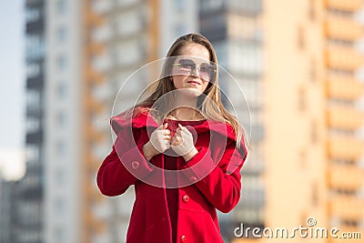 Beautiful girl in a red coat and glasses on the background of the house Stock Photo