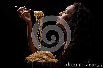 A beautiful girl eats with a fork spaghetti with red lips. Stock Photo