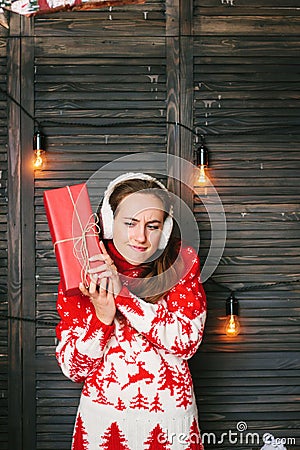 Beautiful girl in a red sweater wondering what inside christmas box - christmas and new year concept Stock Photo