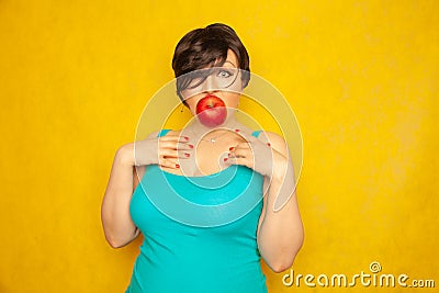 Beautiful girl with a short haircut with a red Apple in her mouth calls for a healthy lifestyle. a woman holds a juicy big Apple w Stock Photo