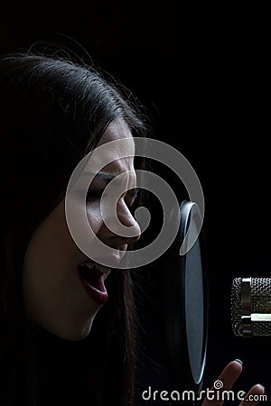 Beautiful girl singing In Recording Studio with microphone Stock Photo