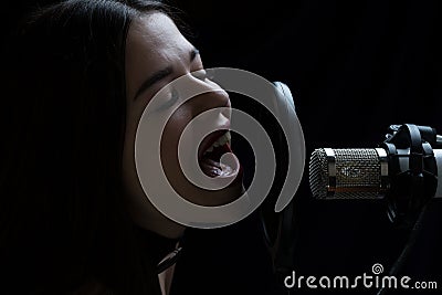 Beautiful girl singing In Recording Studio with microphone Stock Photo