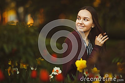Beautiful girl sits at the planted flowers. Stock Photo