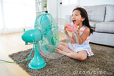 Beautiful girl sitting in front of electric fan Stock Photo