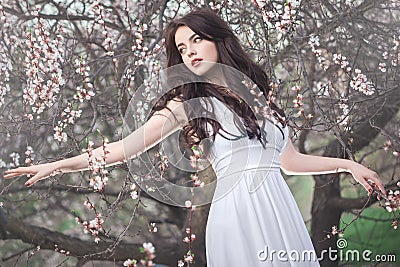 Beautiful girl standing at blossoming tree in the garden Stock Photo