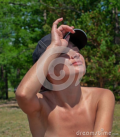 Beautiful girl sunbathes in nature, straightens her cap Stock Photo