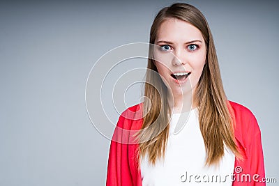 Beautiful girl is surprised by raising eyebrows and opening her mouth looking into the camera Stock Photo