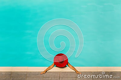 Beautiful girl in a swimsuit and a red hat in a blue water pool Stock Photo