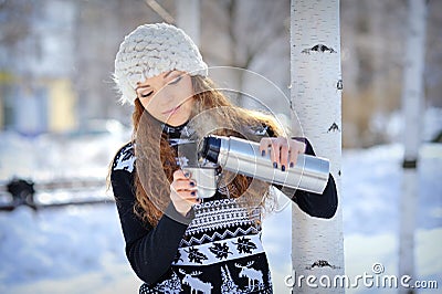 Beautiful girl with thermos and cup hot tea in frosty winter day Stock Photo