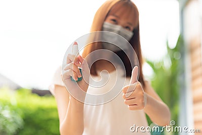 Beautiful girl using disinfectant alcohol spray. A girl wearing a surgical mask. Ways to prevent spreading.Ways to prevent the spr Stock Photo