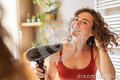 Happy smiling woman using hair dryer in bathroom Stock Photo