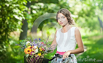 Beautiful girl wearing a nice white dress having fun in park with bicycle. Healthy outdoor lifestyle concept. Vintage scenery Stock Photo