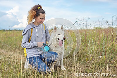 Beautiful girl with white dog, teenager walking with husky pet Stock Photo