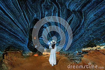 Beautiful girl in white dress walking in blue cave, Thailand Stock Photo