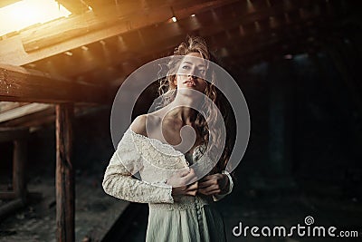 Beautiful girl in in white vintage dress with curly hair posing on the attic. Woman in retro dress. Worried sensual emotion . Retr Stock Photo