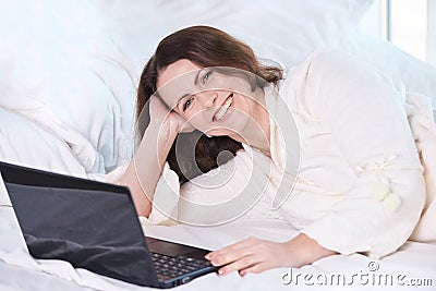 Beautiful girl. Work at home. Black notebook. White Bed Stock Photo