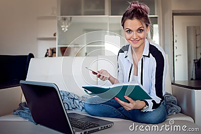 Smiling woman hold her planner. Beautiful girl working at home with laptop. freelance blogger or student Stock Photo