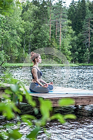Beautiful girl in a yoga pose on the lake. Lotus position , Padmasana. The concept of appeasement, healthy lifestyle. Panoramic Stock Photo