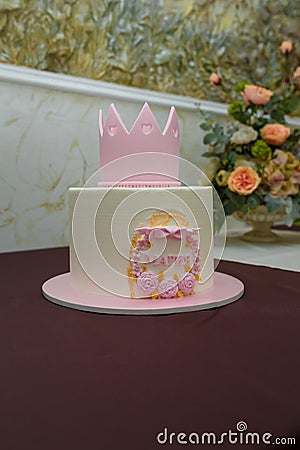 Beautiful girlish birthday cake with pink mastic crown, roses, bow, inscription name Maria. One year old or five years old Stock Photo