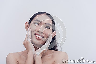 A beautiful and glowing Asian lady pampers herself with whitening facial wash to achieve the desired skin fairness. Stock Photo